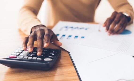 Budget Planning. Unrecognizable black businessman using calculator, tracking income and expenses. Panorama, copy space